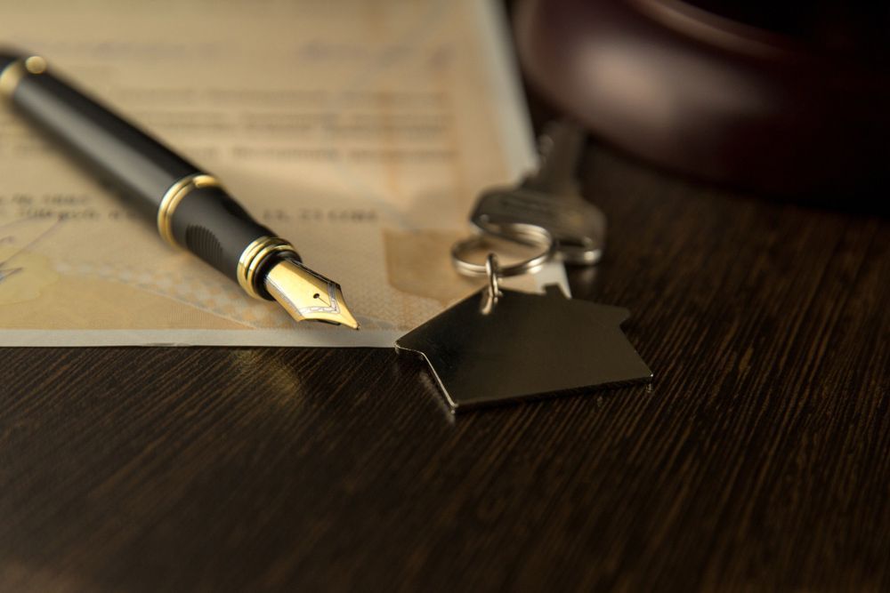 A Fountain Pen Is Sitting on Top of A Piece of Paper Next to A House Key — A M Conveyancing Pty Ltd In Tweed Heads, NSW