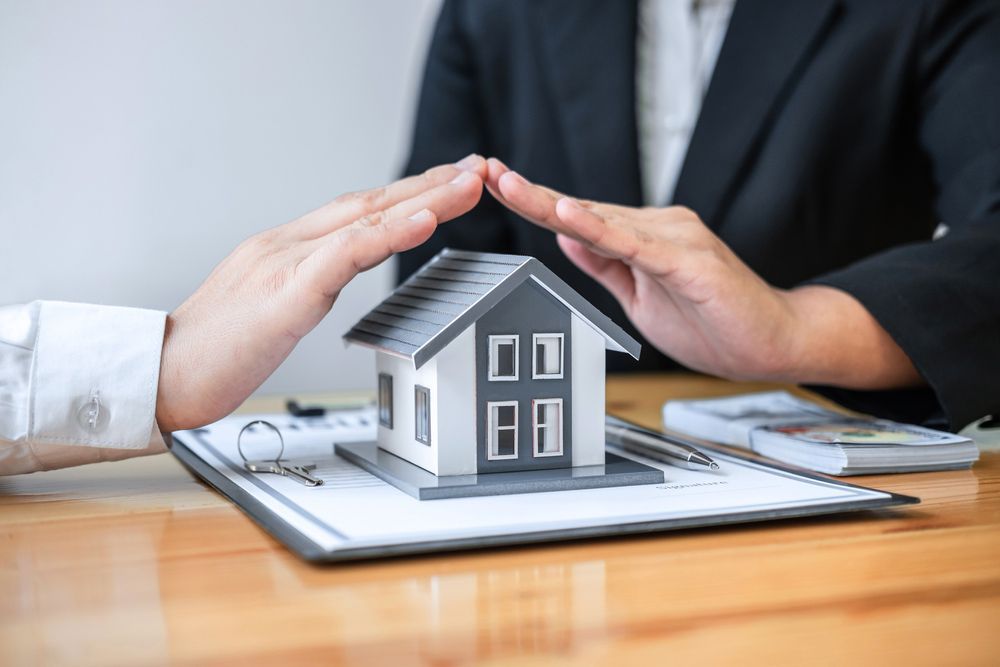 A Person Is Covering a Model House with Their Hands — A M Conveyancing Pty Ltd In Tweed Heads, NSW