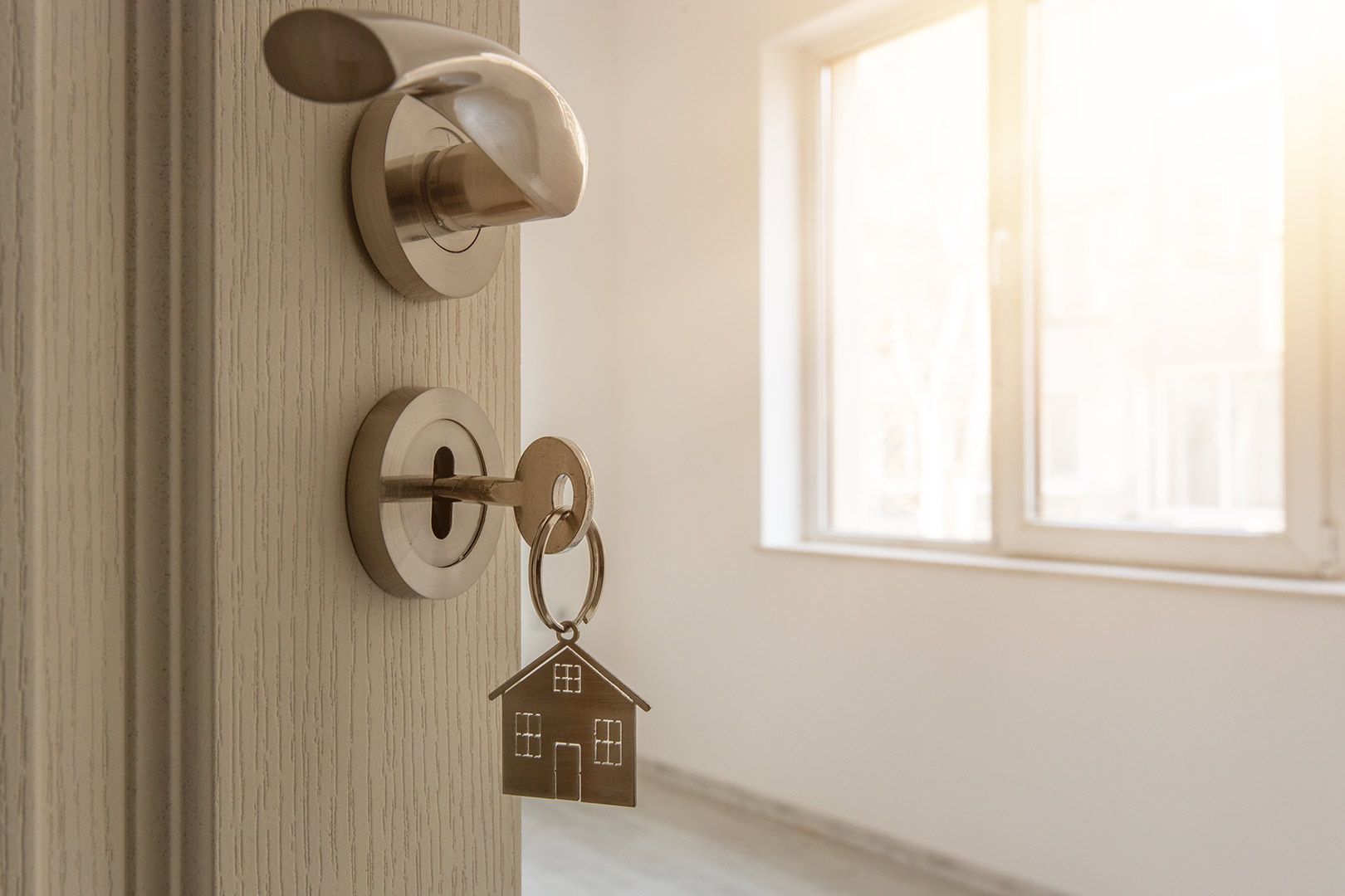 A Door with A Key in It and A Keychain in The Shape of A House — A M Conveyancing Pty Ltd In Tweed Heads, NSW