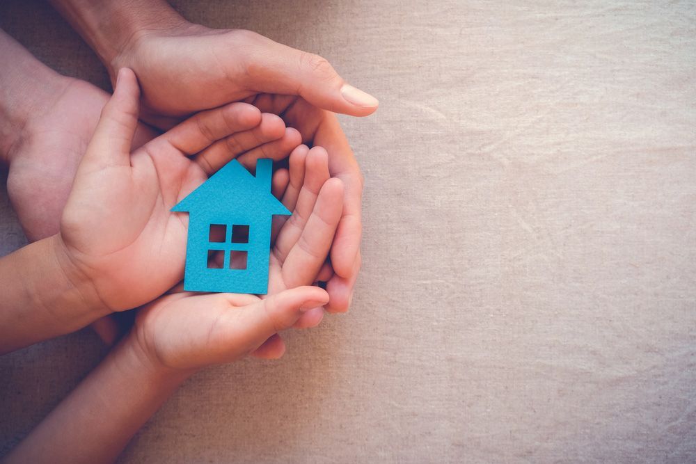 A Man and A Child Are Holding a Blue House in Their Hands — A M Conveyancing Pty Ltd In Palm Beach, QLD