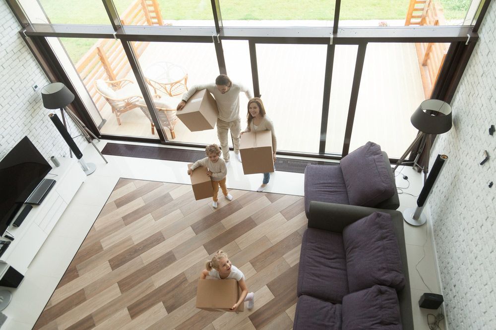 A Family Is Moving Into a New Home and Carrying Cardboard Boxes — A M Conveyancing Pty Ltd In Northern Rivers, NSW