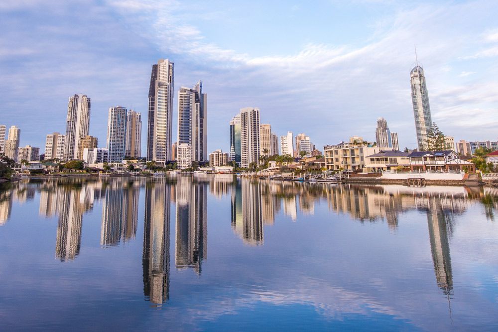 A City Skyline Is Reflected in A Body of Water — A M Conveyancing Pty Ltd In Gold Coast, QLD