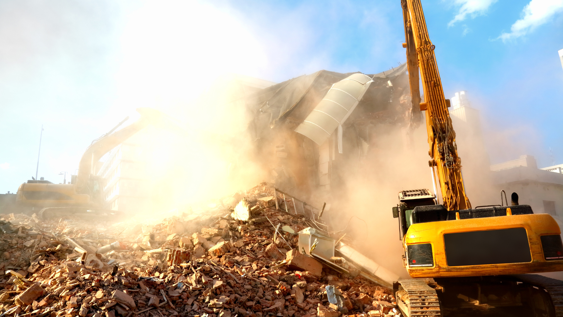 a large yellow excavator is demolishing a building .