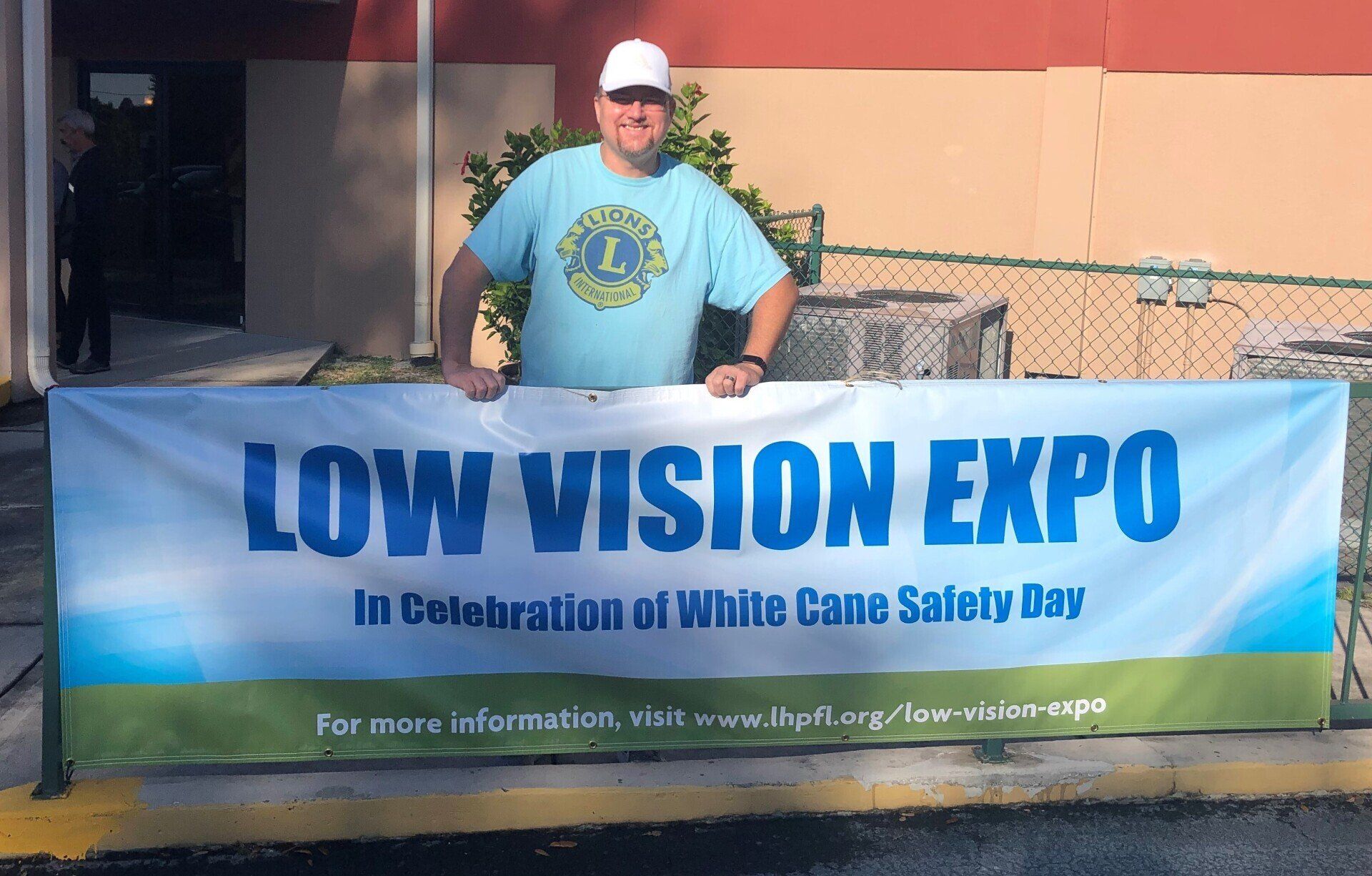 A man holding a sign that says low vision expo