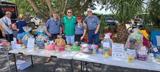 A group of people are standing around a table filled with lots of gifts.