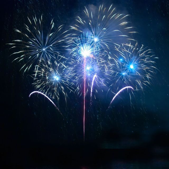 Fuochi d’artificio blu e bianchi che esplodono nel cielo notturno buio