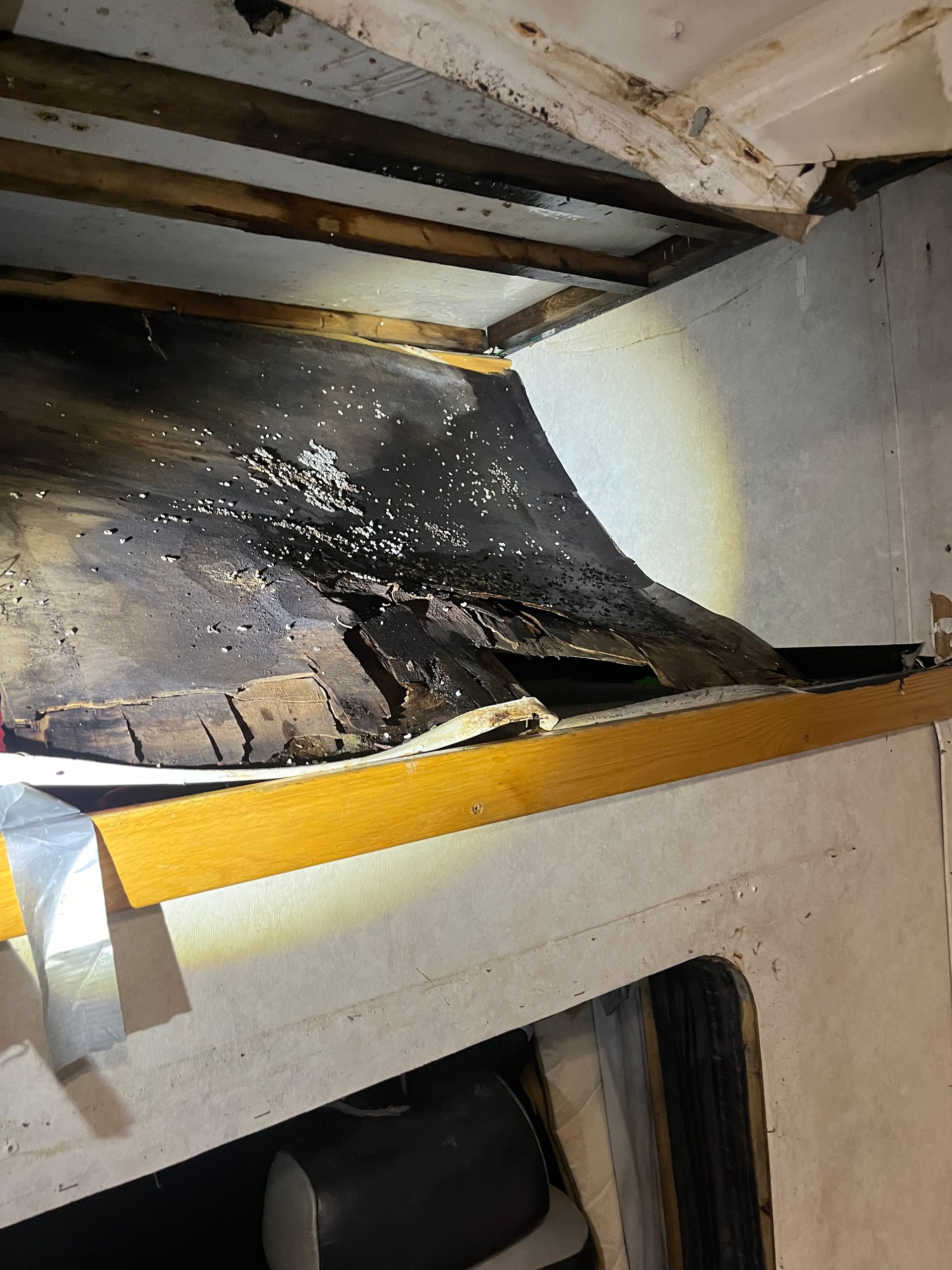 Damaged interior of a boat; rotted wood, white mold, and crumbling structure near a window.