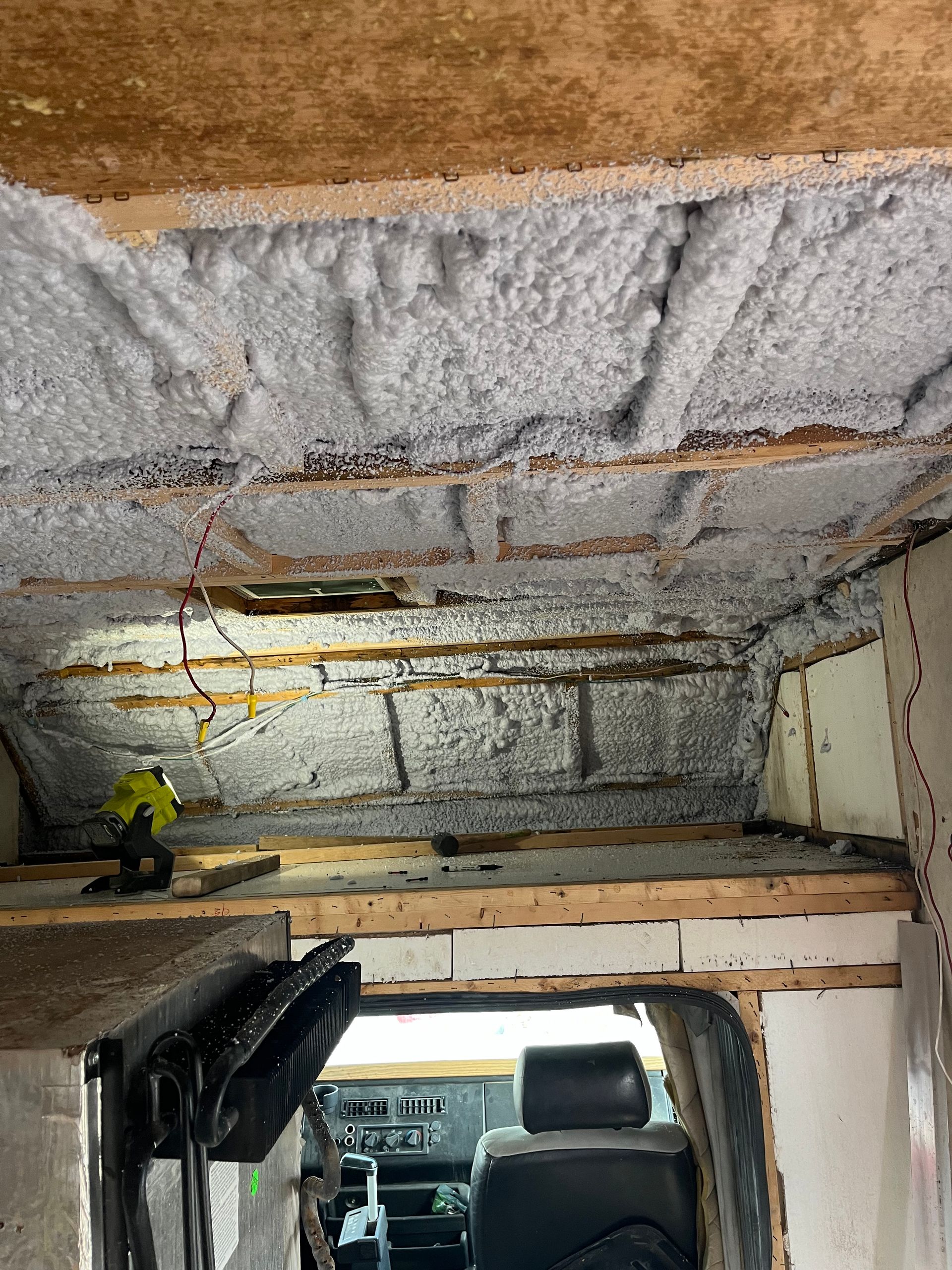 Interior of a van with insulation in the ceiling and walls. A person is visible.