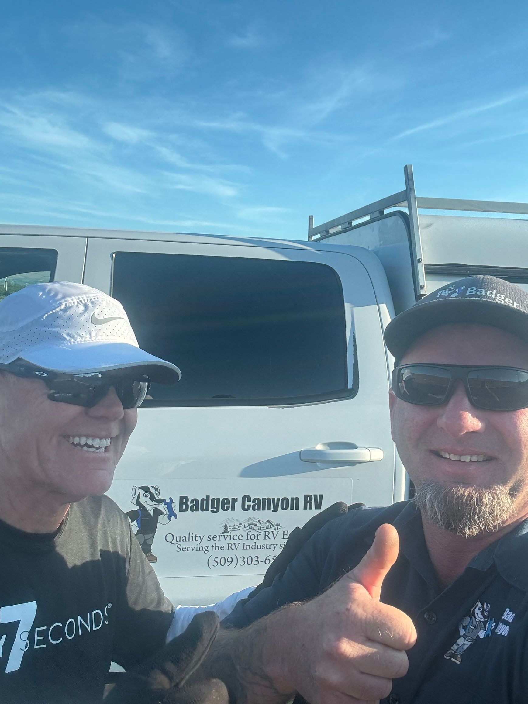 Two men smiling next to a white van with 