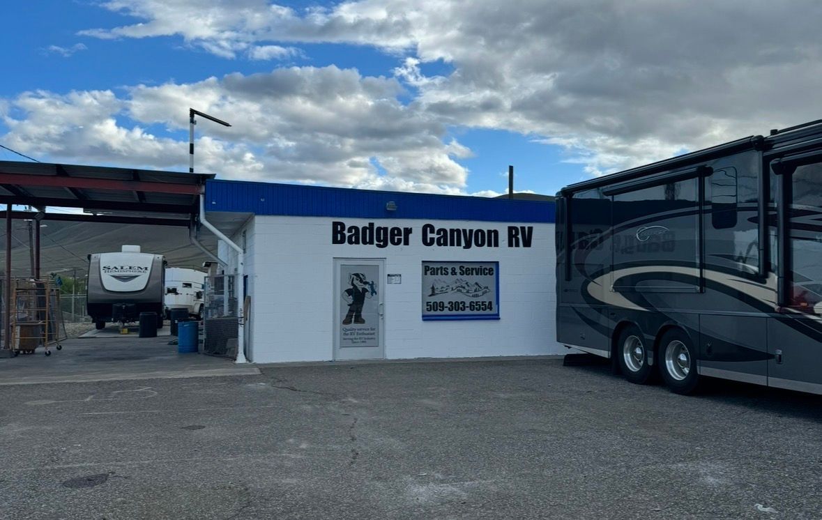 Badger Canyon RV business with a white building and RVs parked outside under a cloudy sky.