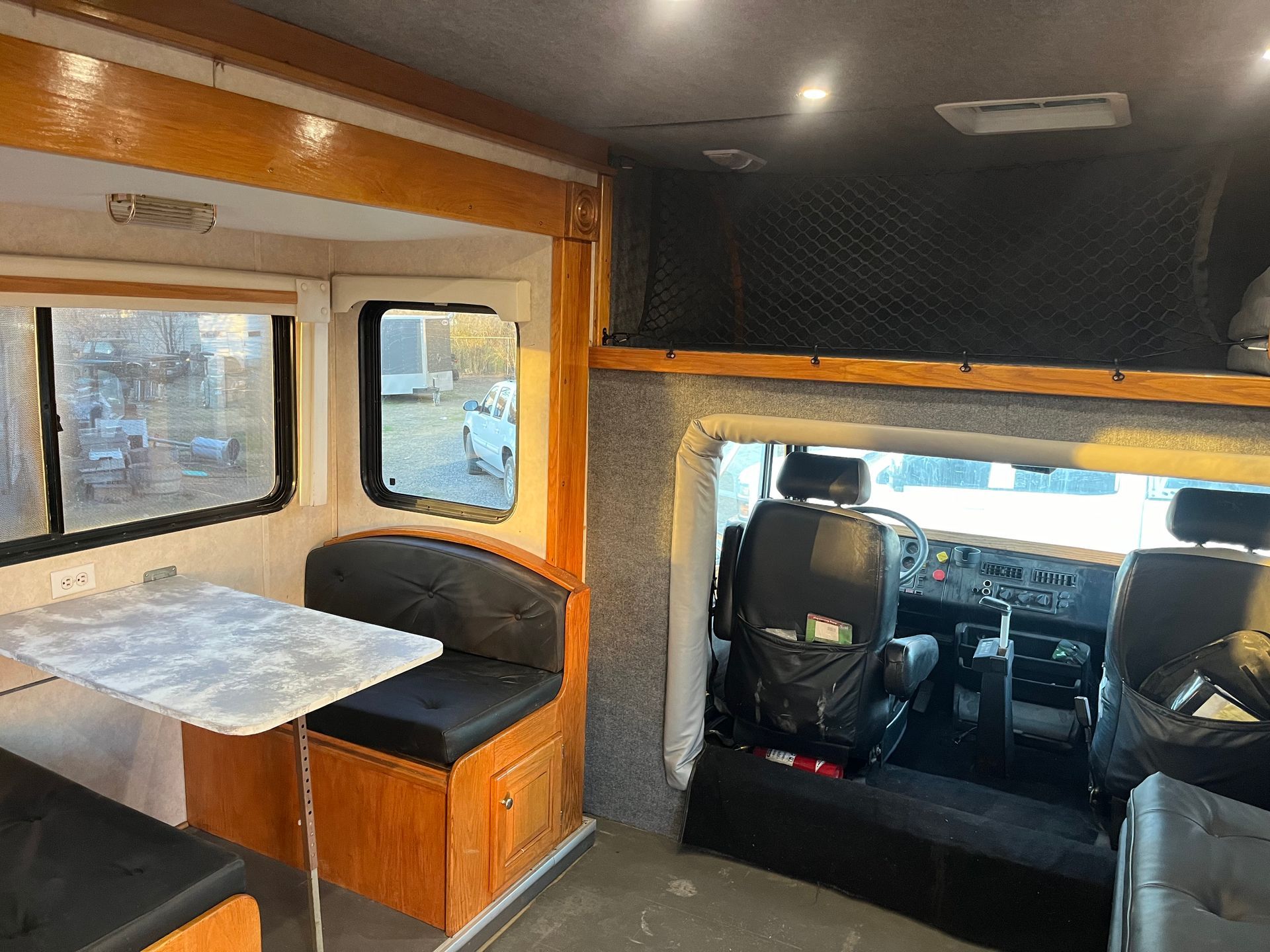 Interior view of a customized camper van featuring a dining area, seating, and a loft bed overlooking the cockpit.
