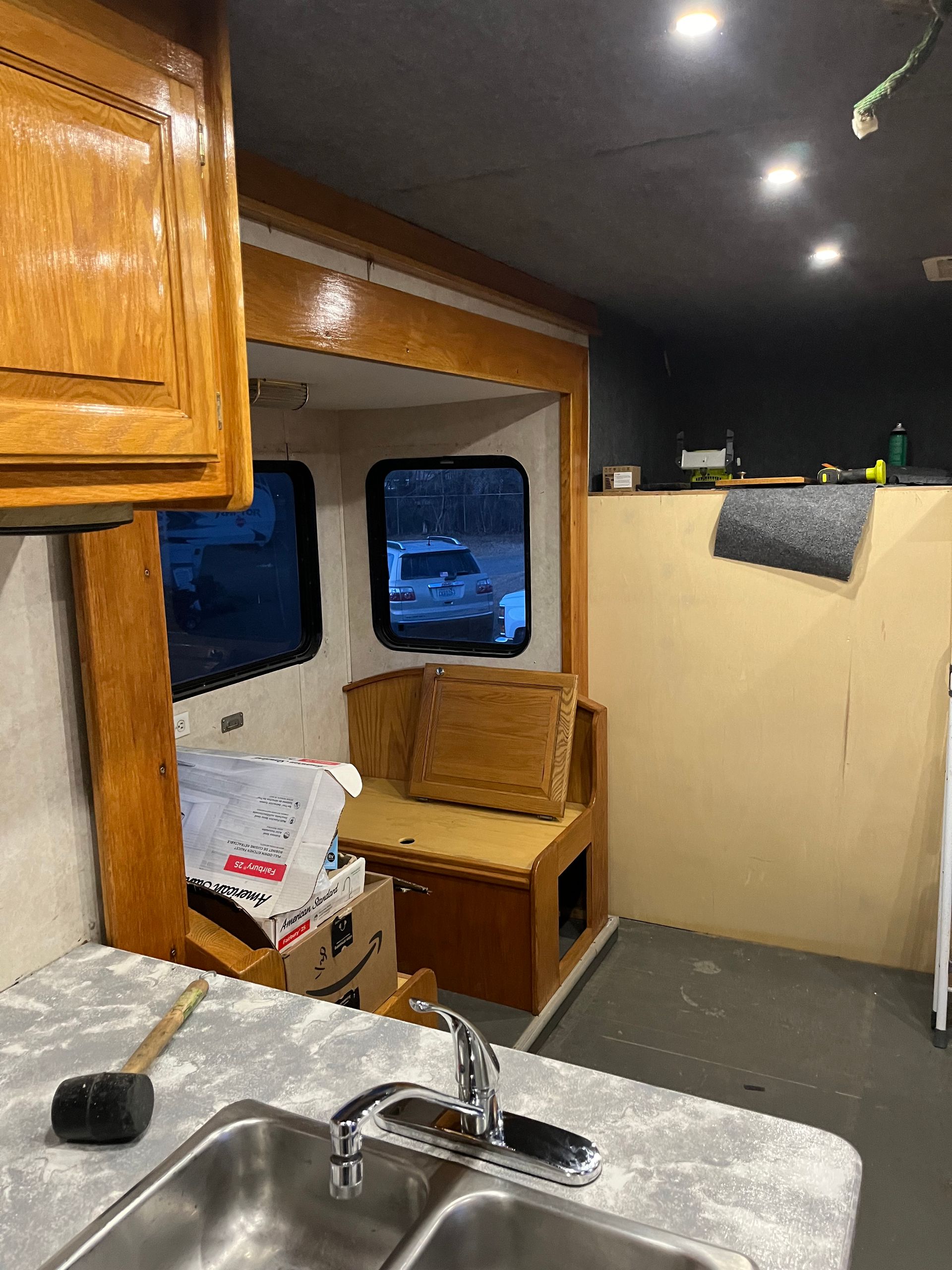 Interior of a camper being renovated; includes a sink, cabinets, a bench, and partially finished walls.