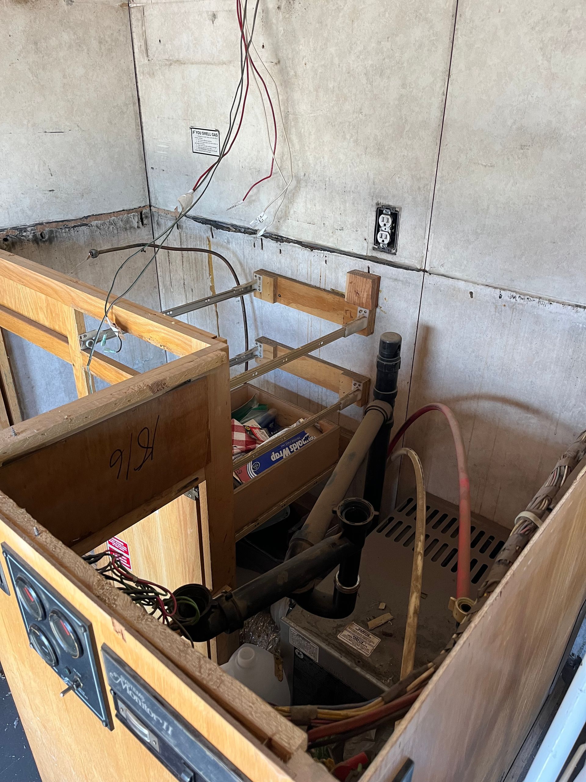Unfinished kitchen with exposed wires, plumbing, and partially constructed cabinets.