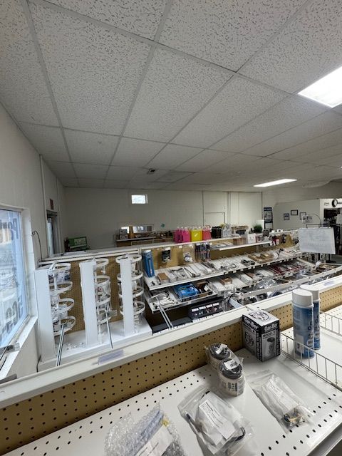 Interior view of a hardware store, displaying shelves of tools and supplies under a white tiled ceiling.