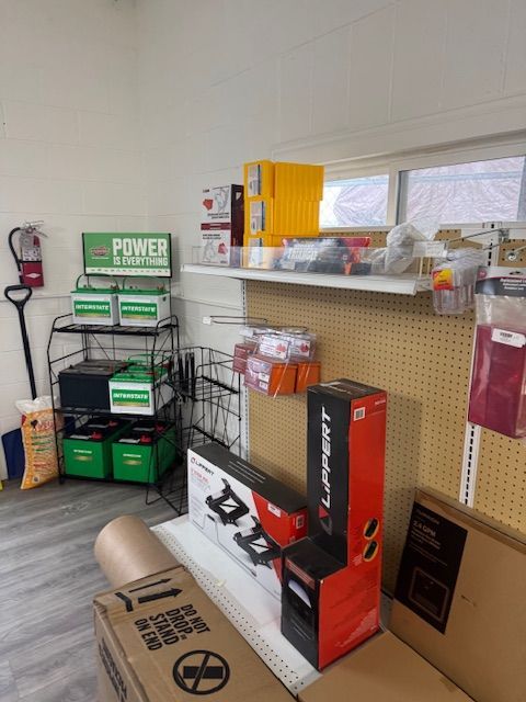 A retail store interior displays batteries, automotive parts, and various supplies on shelves and racks.