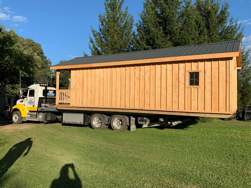 Cabin on flatbed truck on green grass. Yellow and white truck. Sunny day.