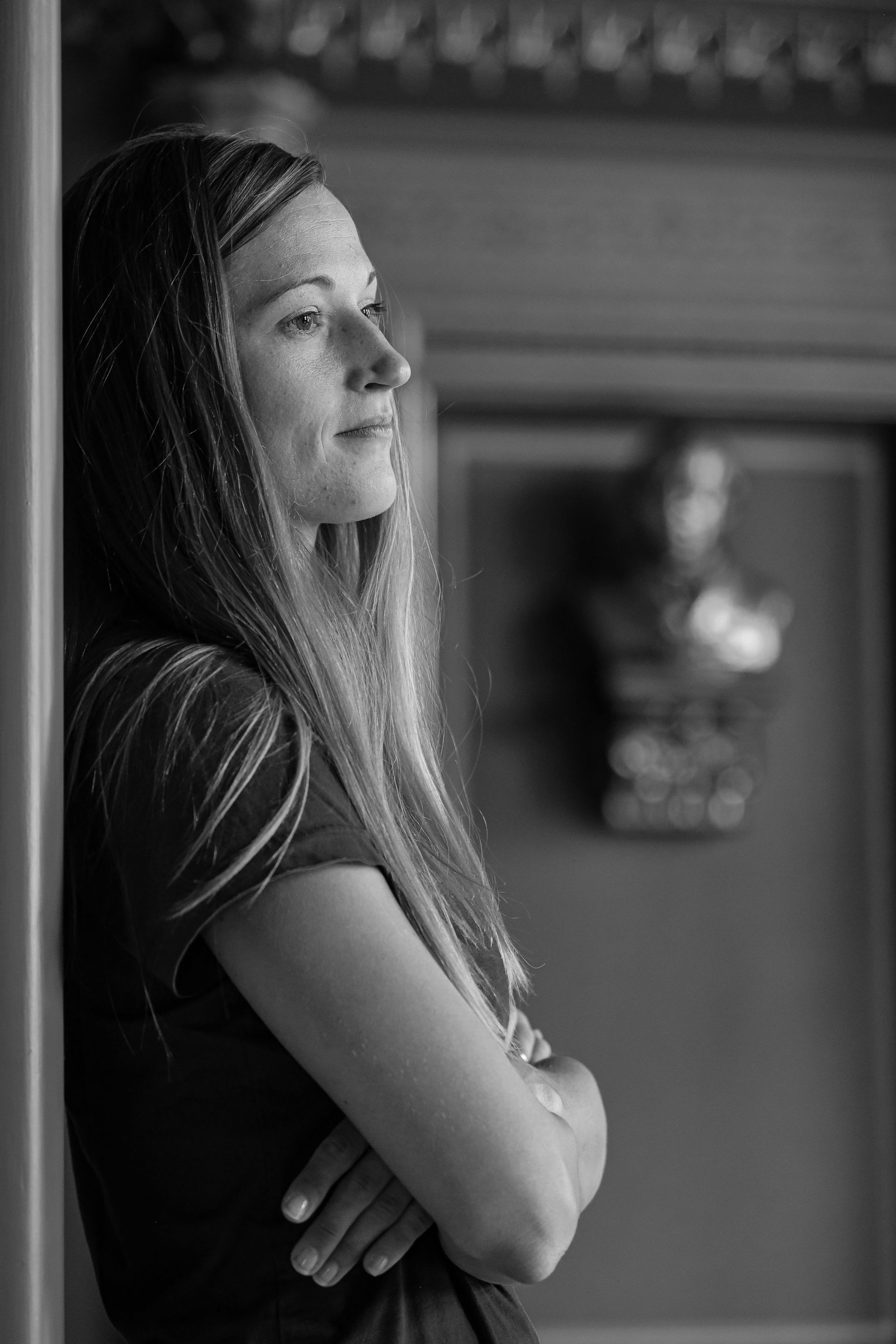 Même dans la douleur la plus profonde, il y a une guérison. Une jeune femme s’appuie contre un mur, les bras croisés, l’air pensif et le regard vide devant elle.