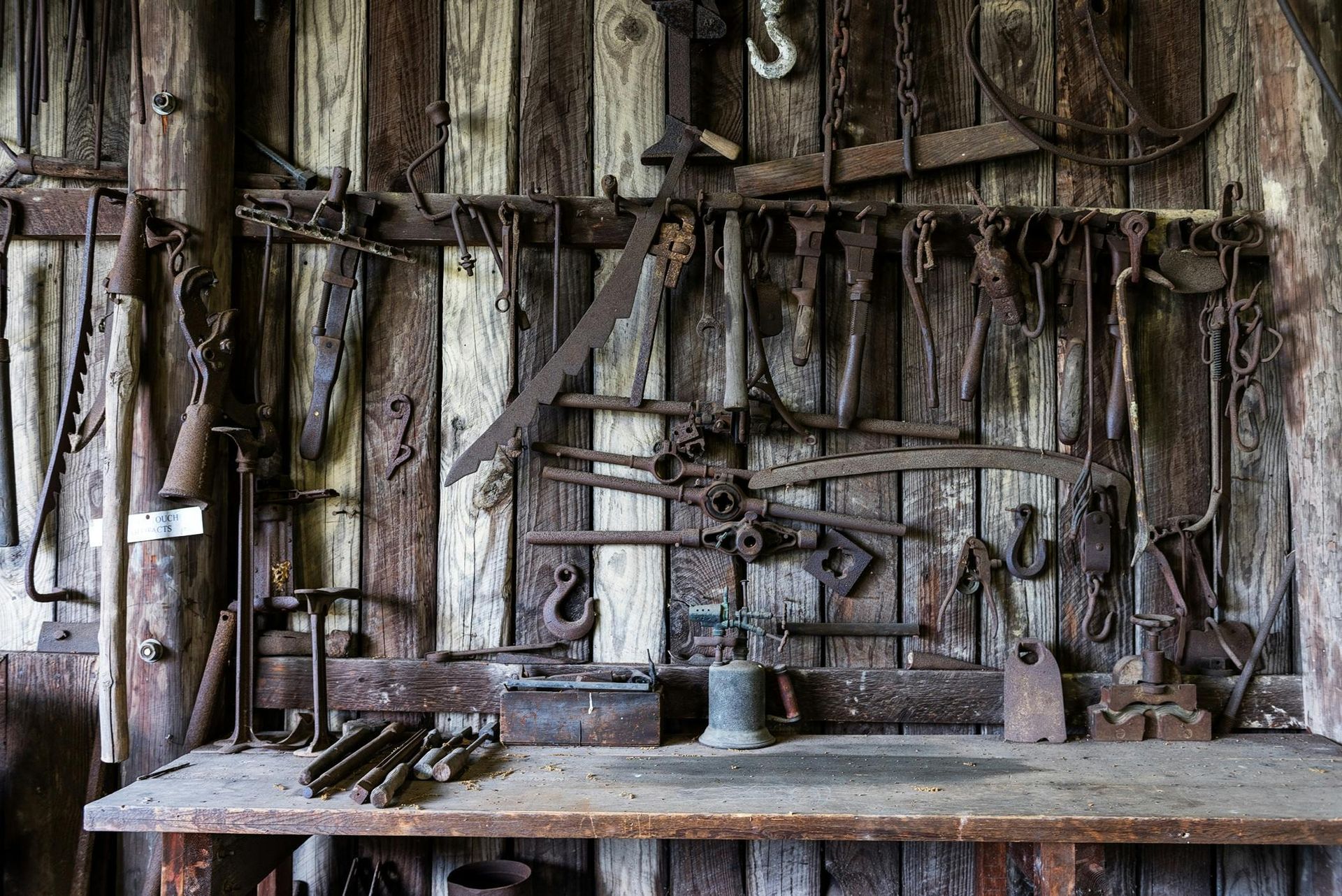 Wie dienlich sind deine Werkzeuge? Eine sehr alte, nostalgische Werkstatt mit vielen verrosteten Werkzeugen aus Stahl an der Wand. Für heutige Zwecke kaum noch zu gebrauchen.