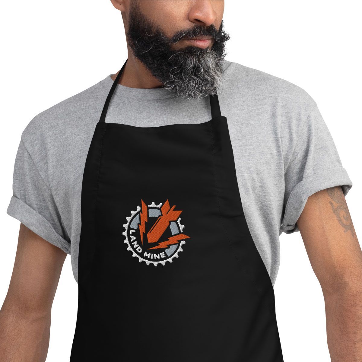 Man in a gray T-shirt wearing a black apron with an orange-and-white logo