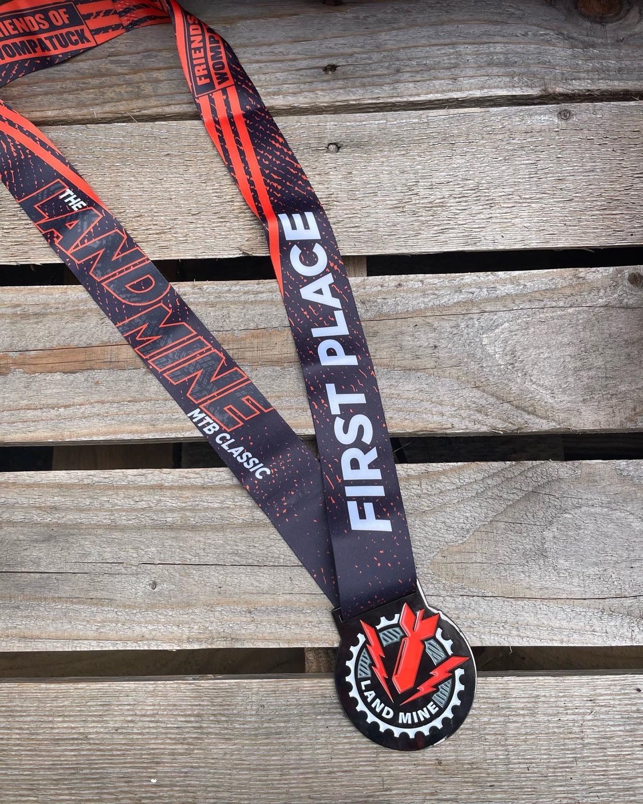 Black and red first-place medal ribbon on weathered wooden boards