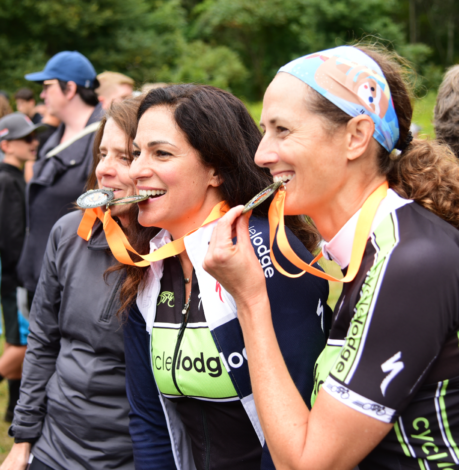 Three women in running gear smile with medals after a race.