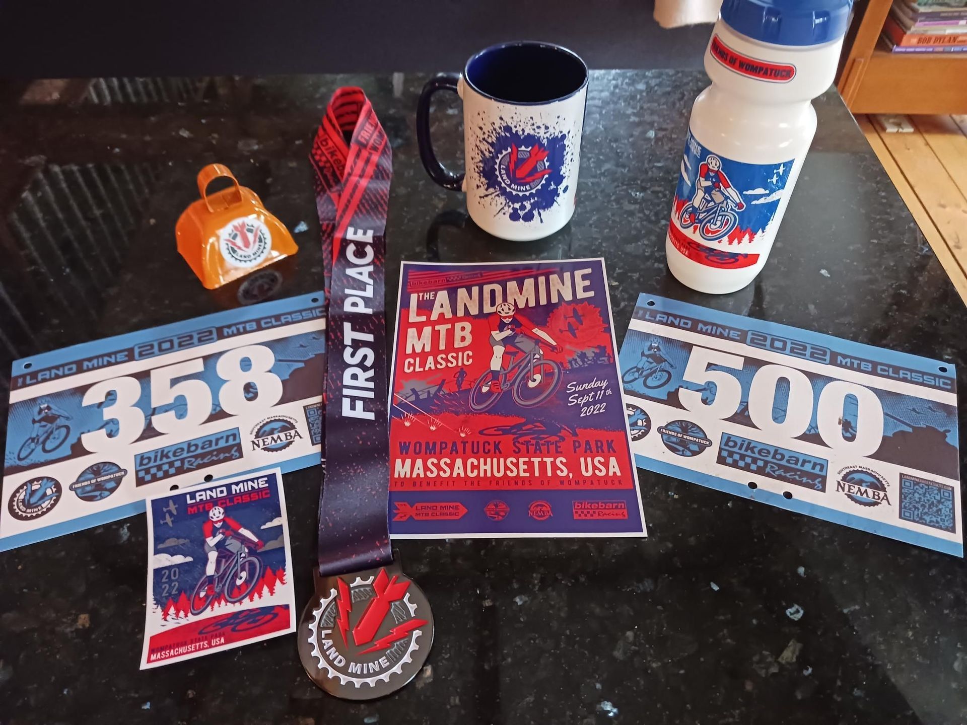 Boston Red Sox memorabilia, including tickets, a mug, bottle, patch, and Landmine home plate sign on a table