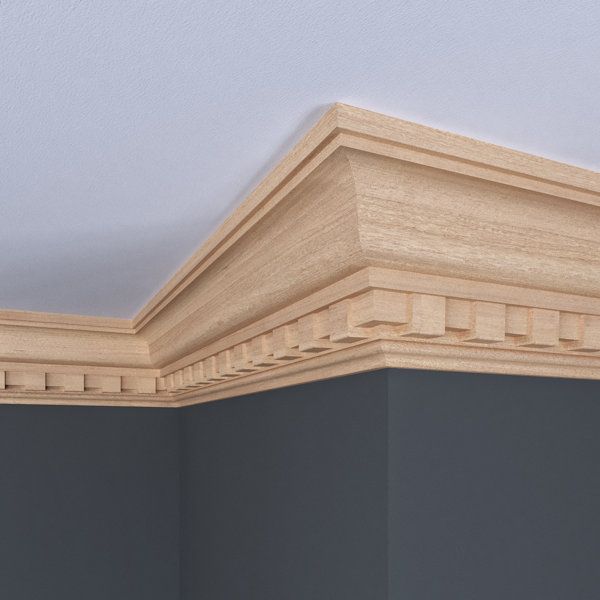 A corner of a room with a wooden molding on the ceiling