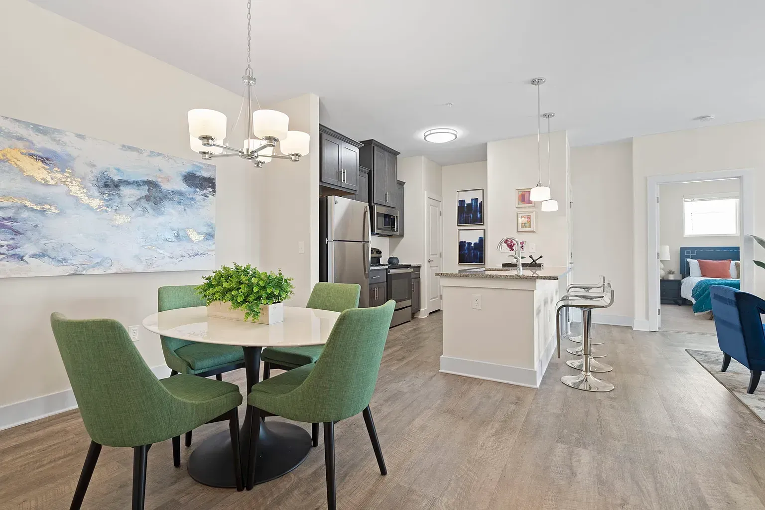 Open-concept apartment interior featuring a dining area with green chairs and a modern kitchen.