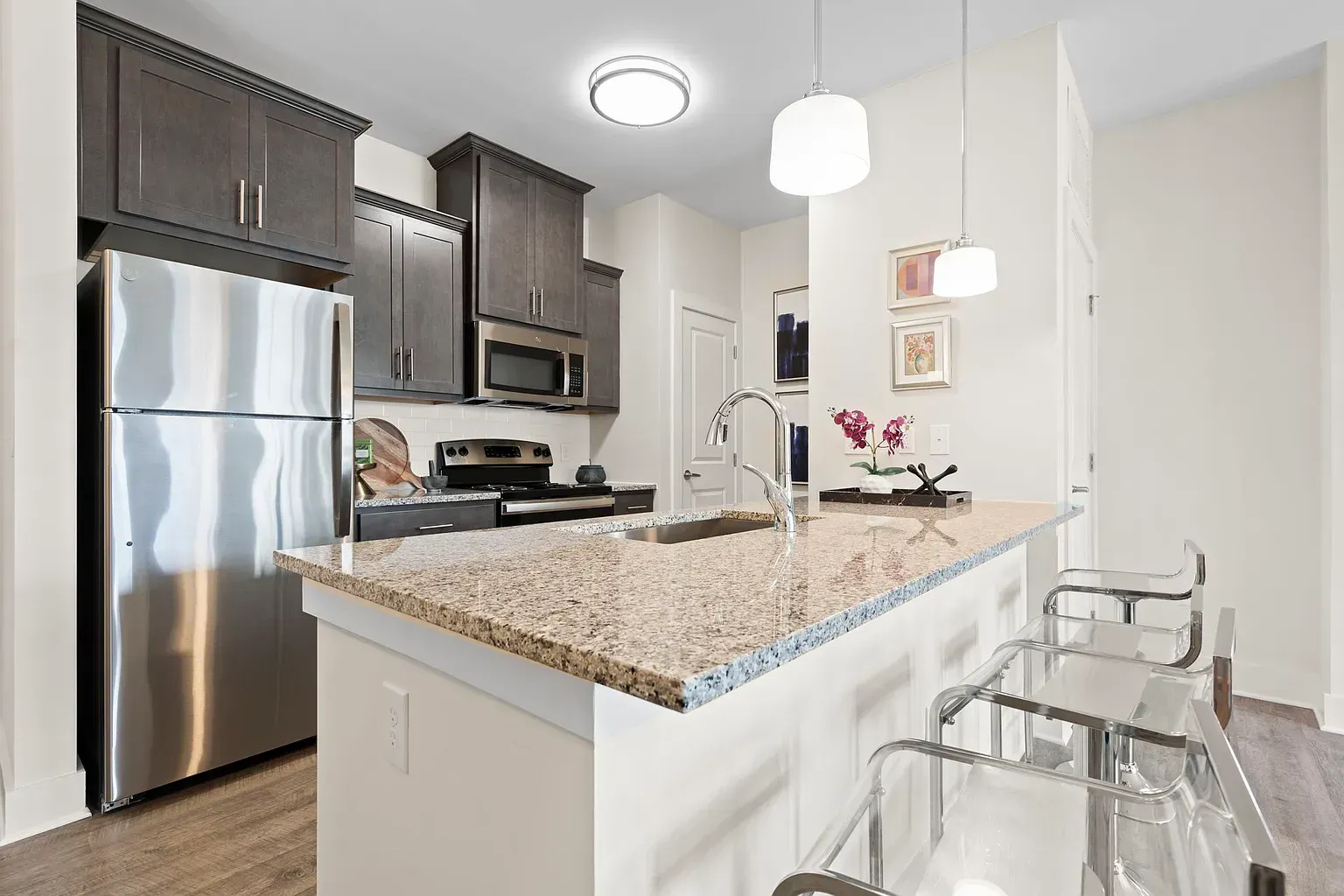 Modern kitchen in an apartment with a granite island, stainless steel appliances, and bar stools.