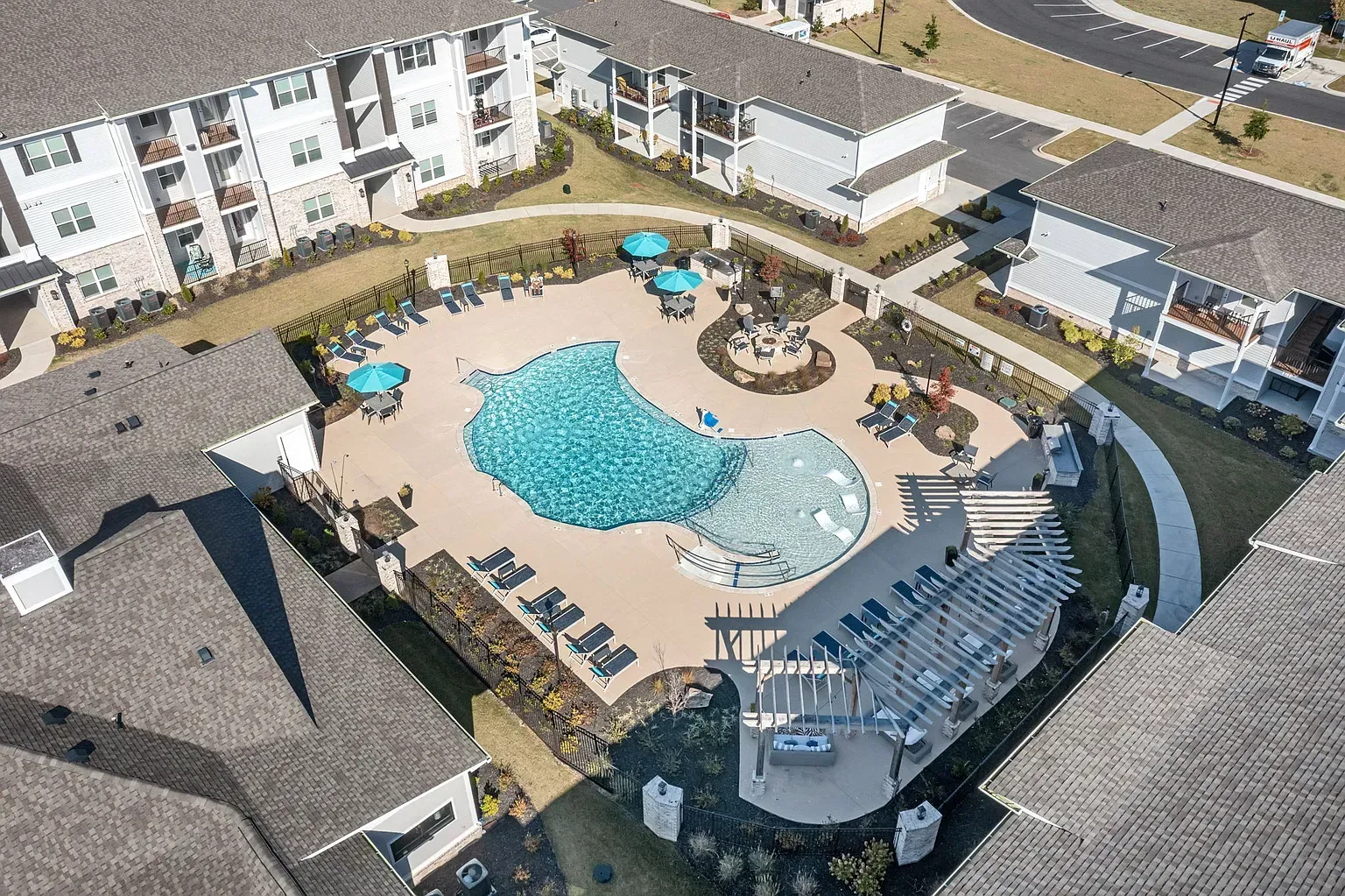 Aerial view of a resort-style apartment community pool with lounge chairs and umbrellas.