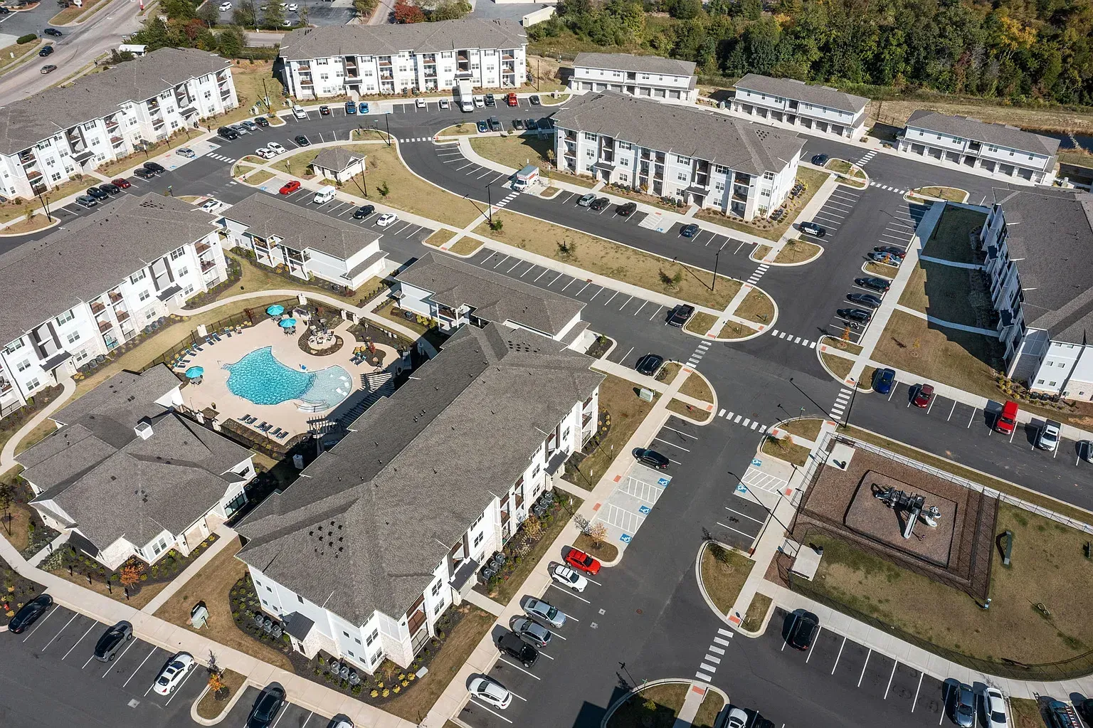 Aerial view of a multi-building apartment community with a central pool and parking.