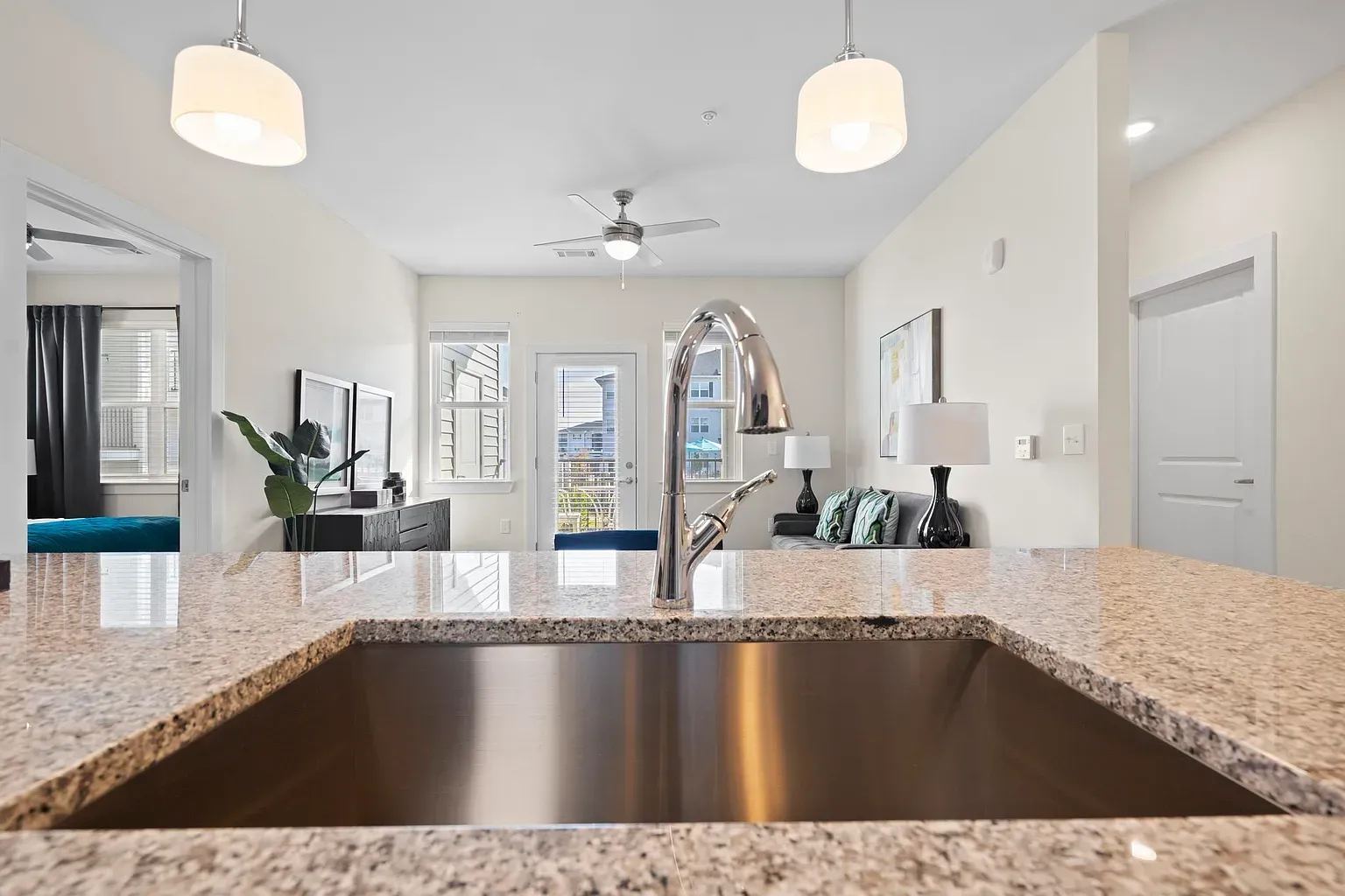 Open-concept kitchen with granite countertop island and stainless-steel sink.