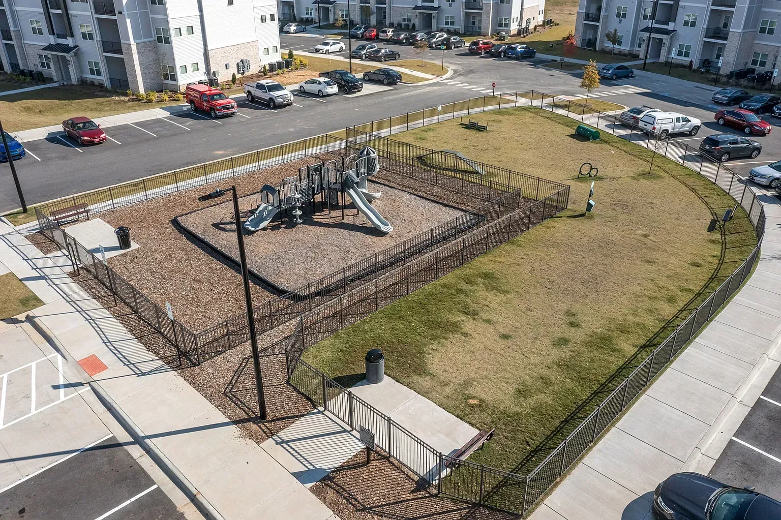 Aerial view of a fenced playground with slides in a residential complex.