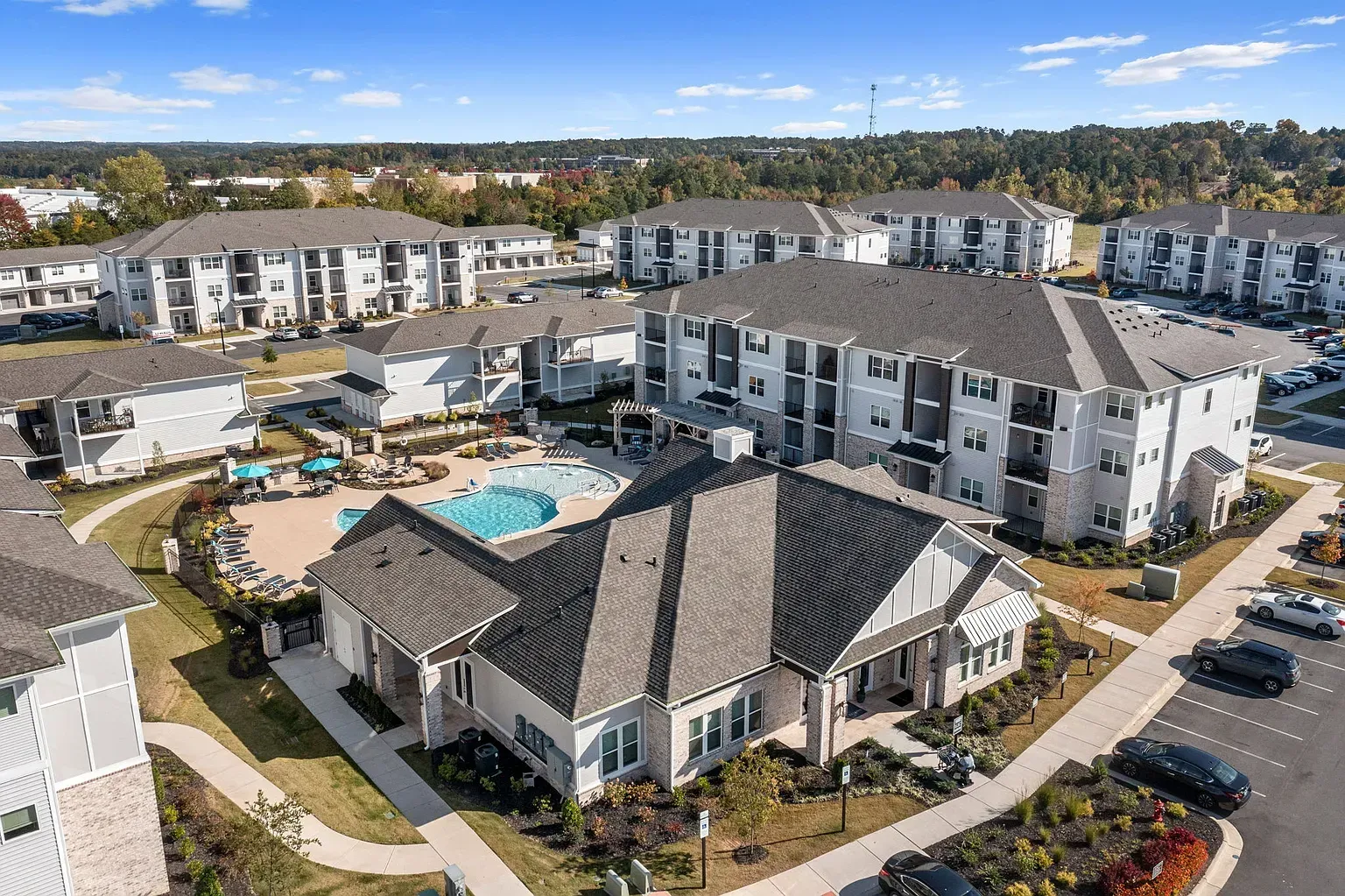 Aerial view of a modern apartment community with a central pool, courtyards, and multiple buildings.