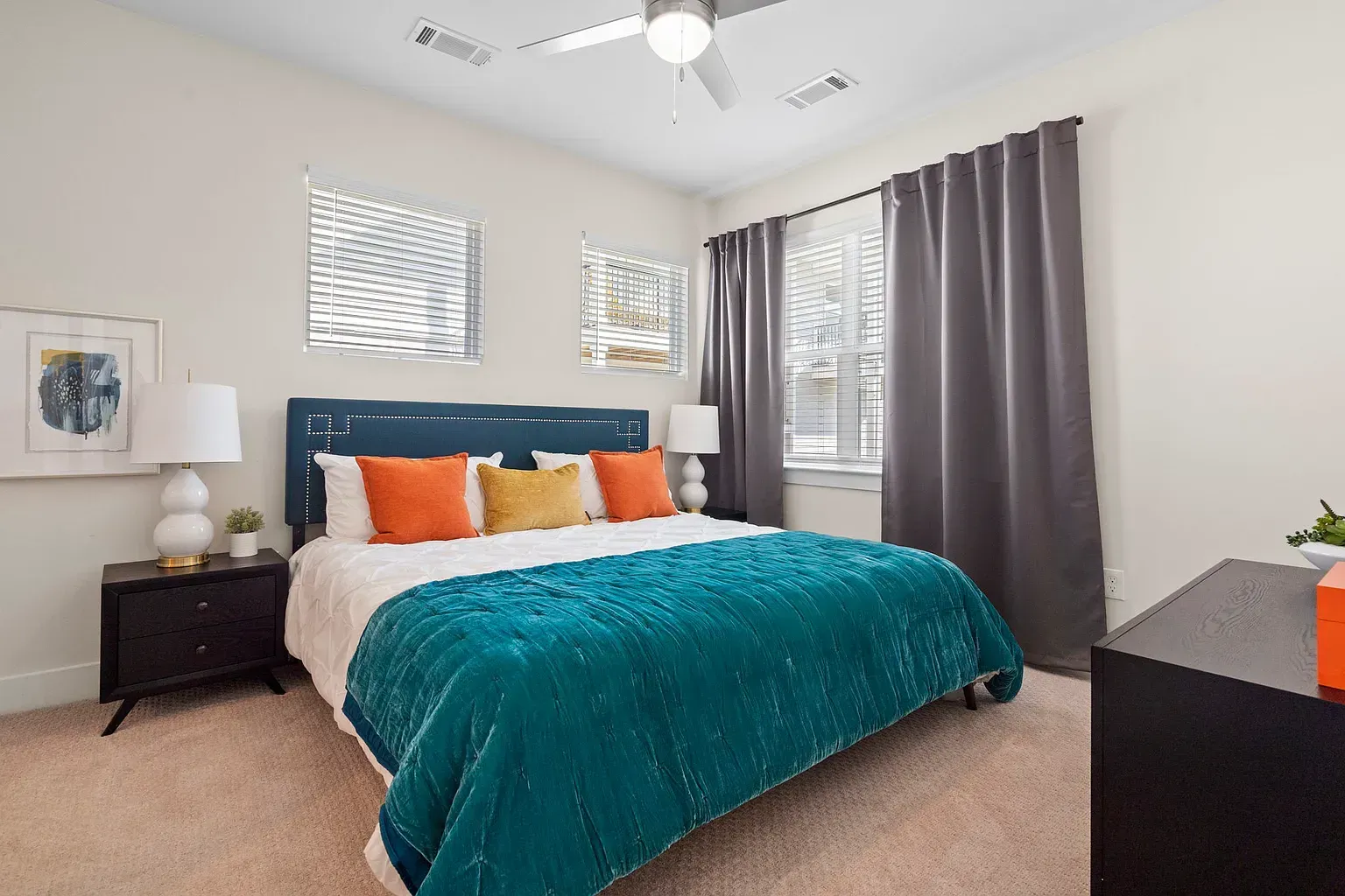 Bright bedroom with teal upholstered headboard, white bedding, and gray curtains.