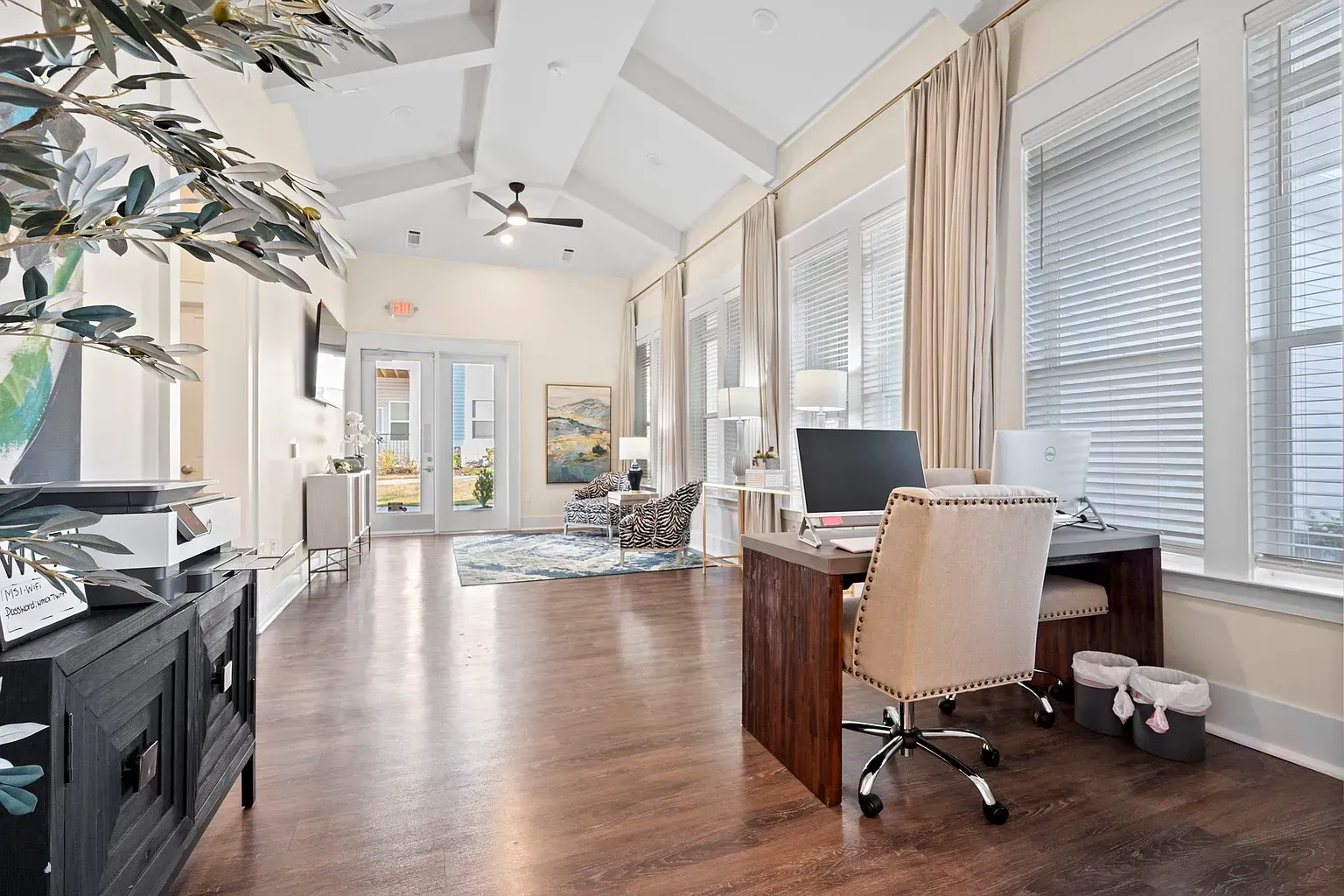 Bright leasing office with desk, computer, and seating near large windows.