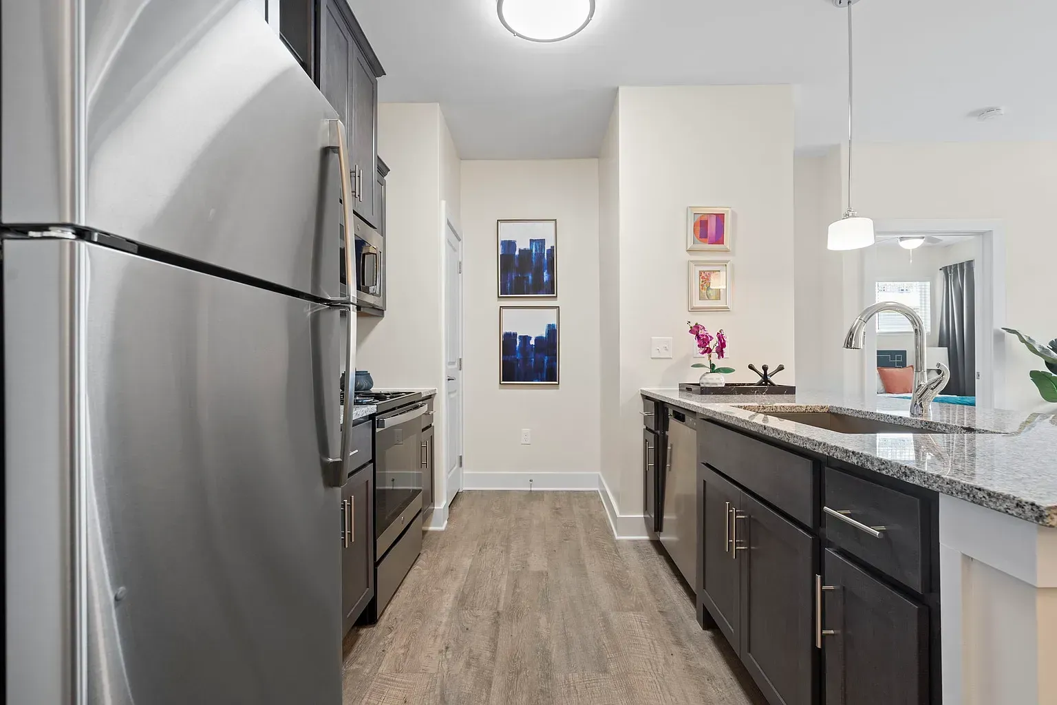 Modern apartment kitchen with stainless steel appliances, granite countertops, and an island.