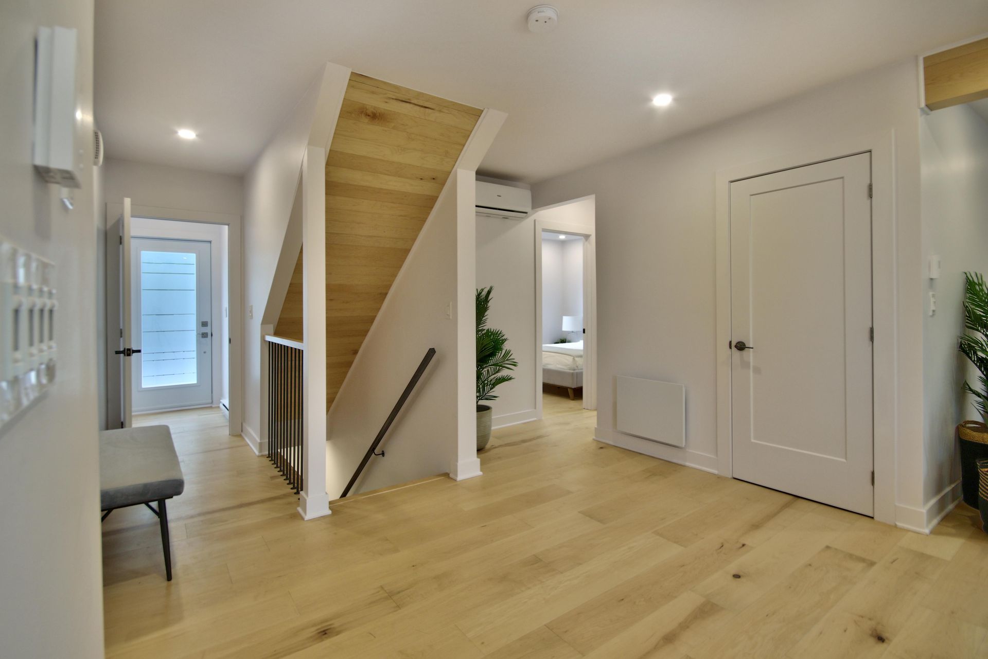A hallway with wooden floors and stairs in a house.