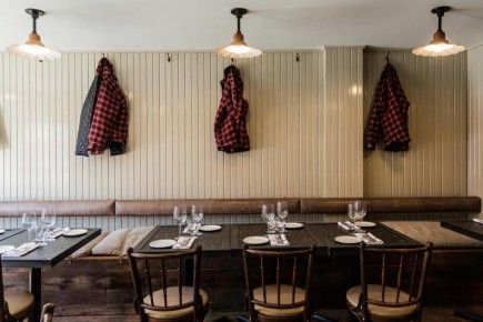 A restaurant with tables and chairs and jackets hanging on the wall.