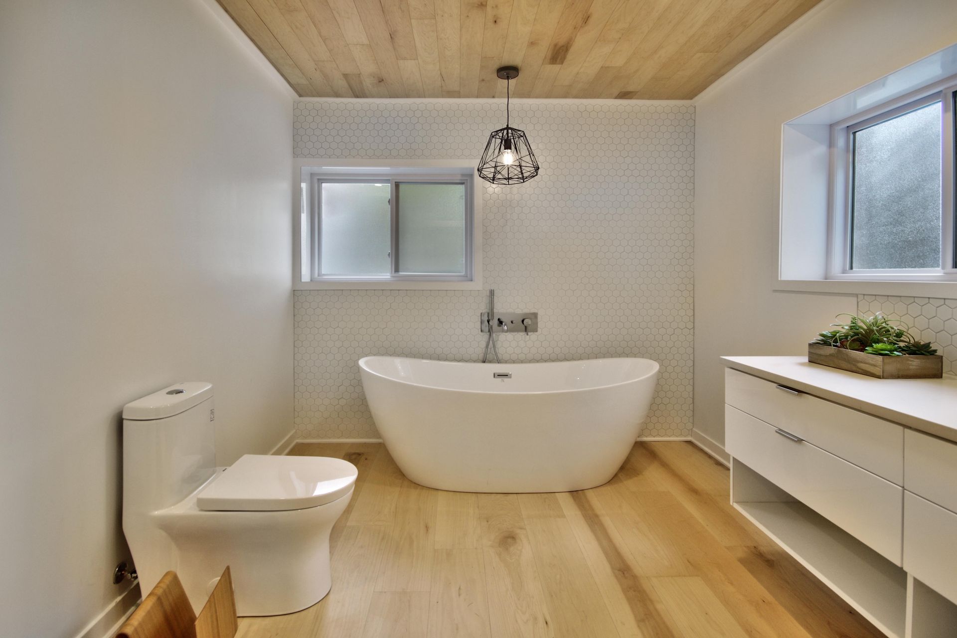 A bathroom with a bathtub , toilet , sink and window.