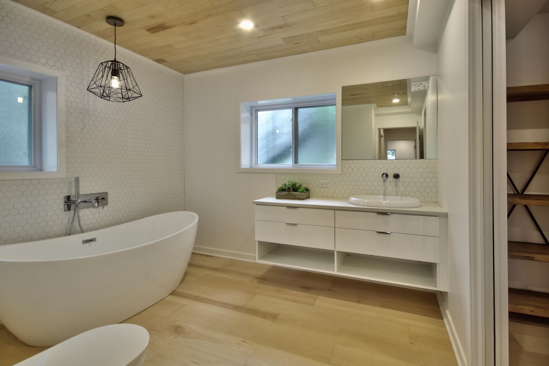 A bathroom with a bathtub , sink , mirror and window.