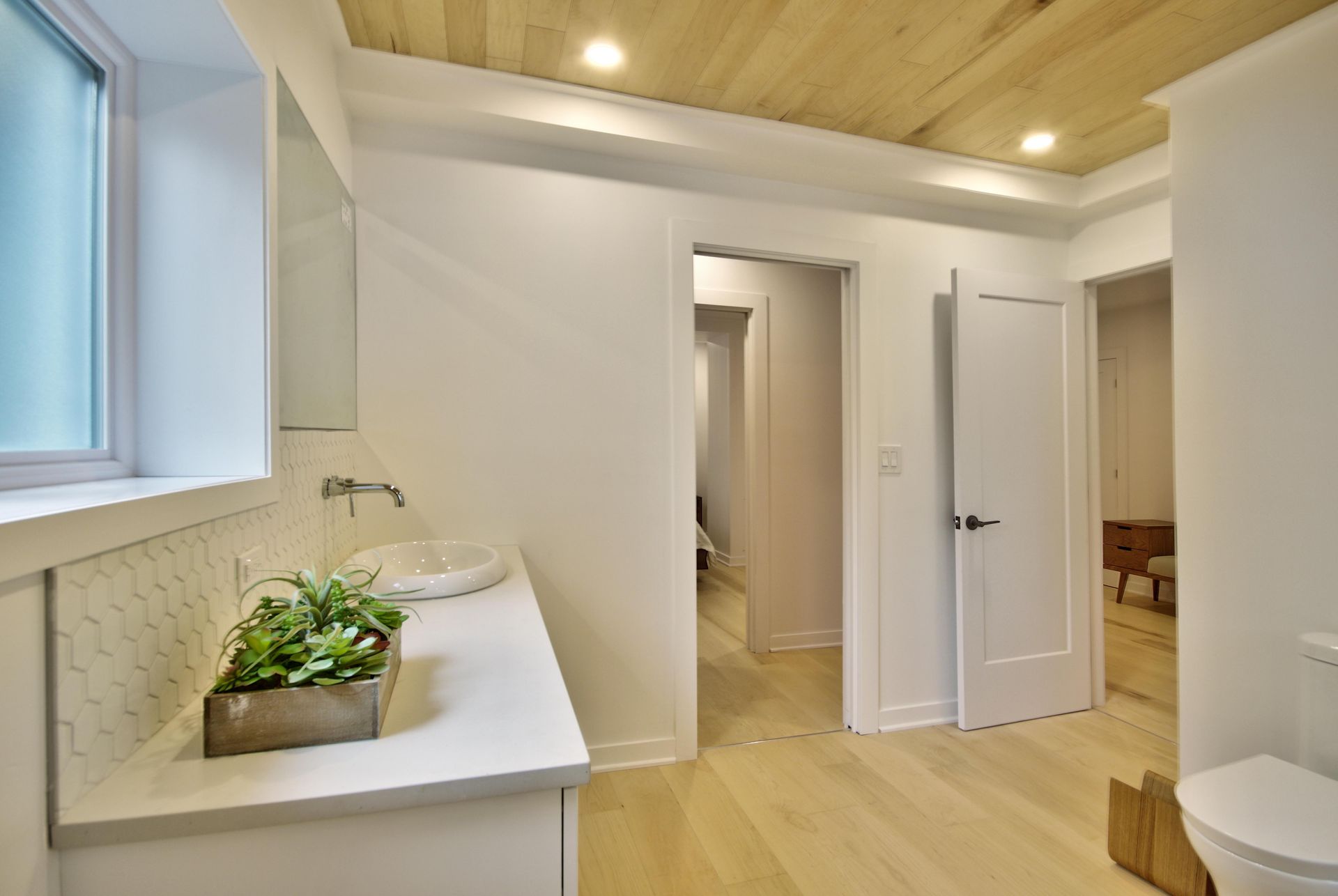 A bathroom with two sinks , a toilet and a window.
