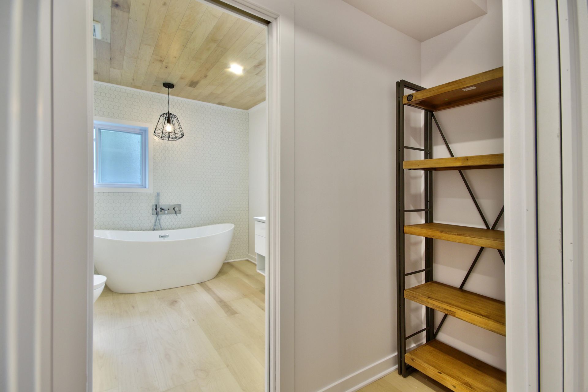 A bathroom with a bathtub and a wooden shelf.