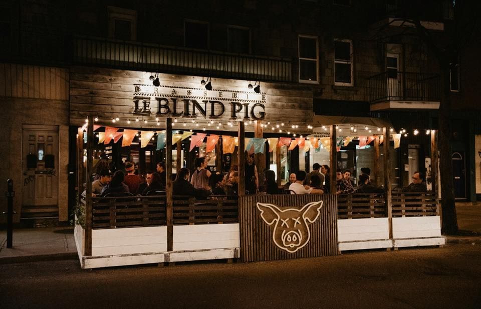 A group of people are sitting outside of a restaurant at night.