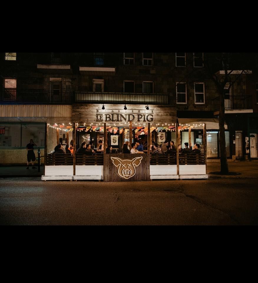 A group of people are sitting outside of a restaurant at night.