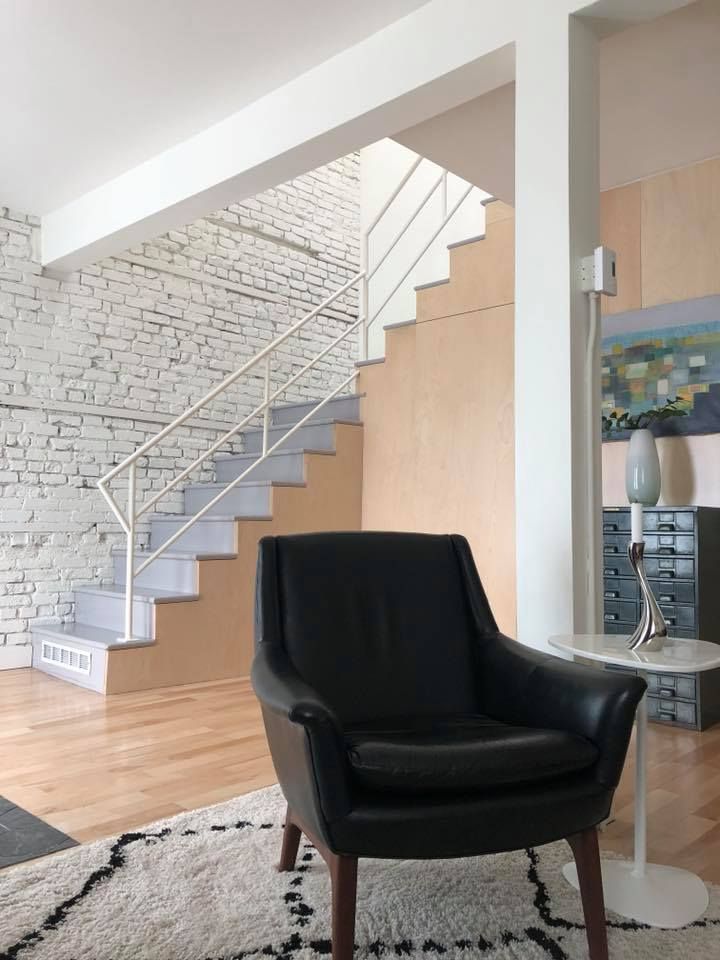 A living room with a black chair and stairs in the background