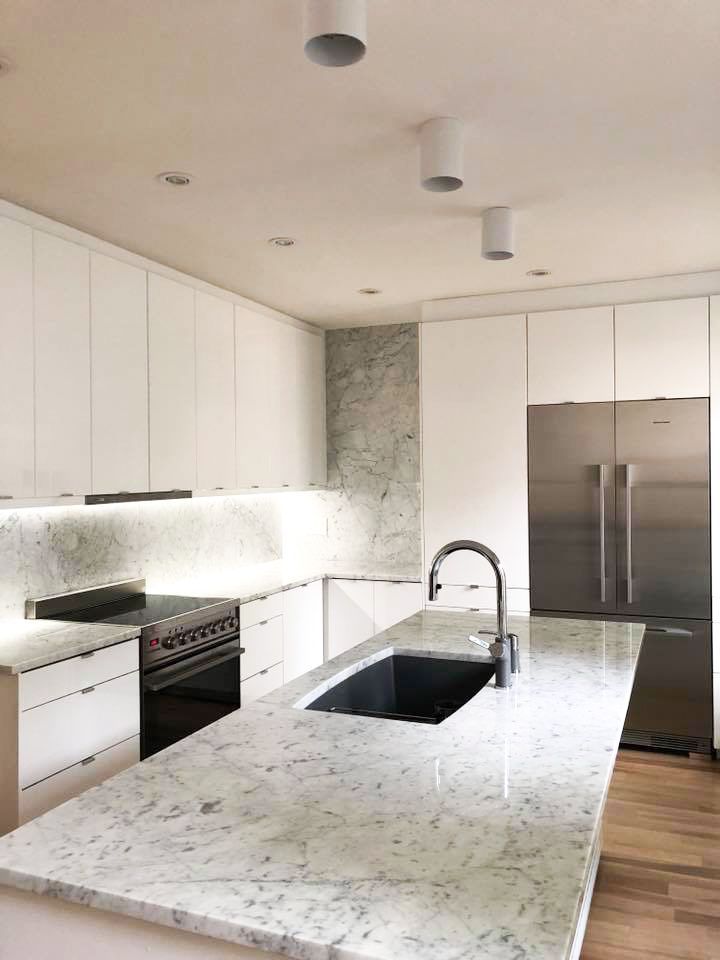 A kitchen with white cabinets , granite counter tops , stainless steel appliances and a large island.
