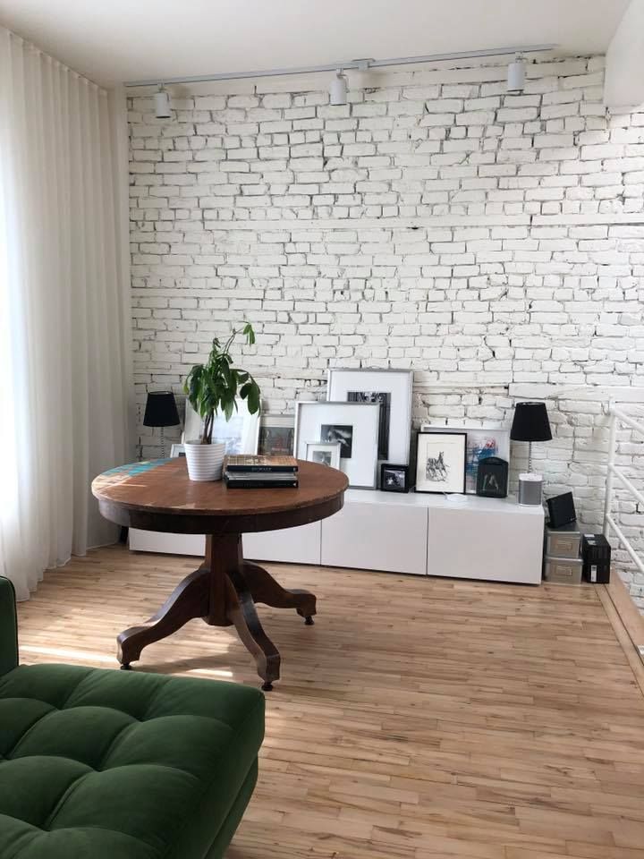 A living room with a white brick wall and a round table.