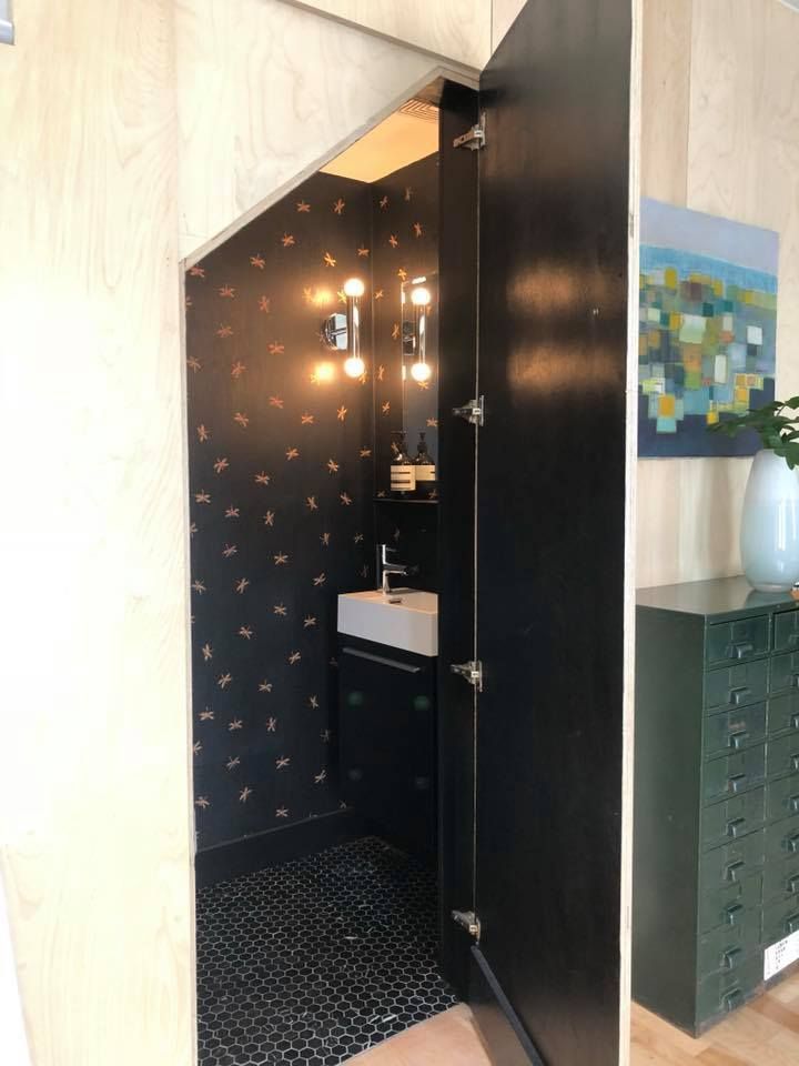 A bathroom with a sink and a mirror under a staircase.