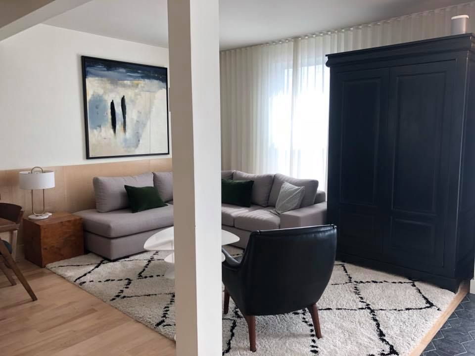 A living room with a couch , chairs , and a rug.